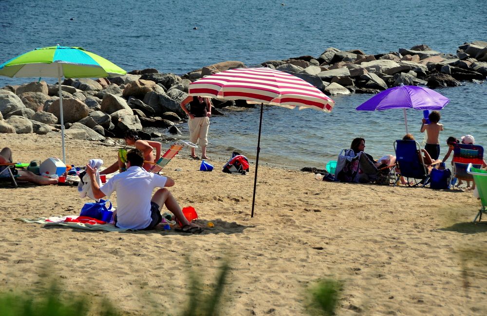 People sitting on the sand of DuBois Beach.