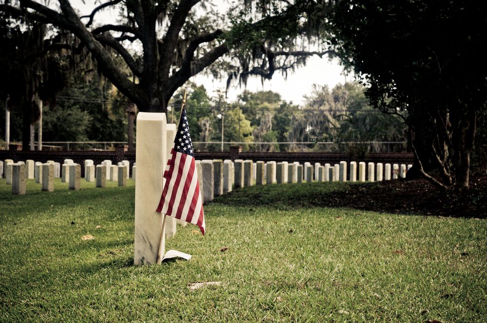 Closeup of tombstone and an american flag at Beaufort National Cemetery