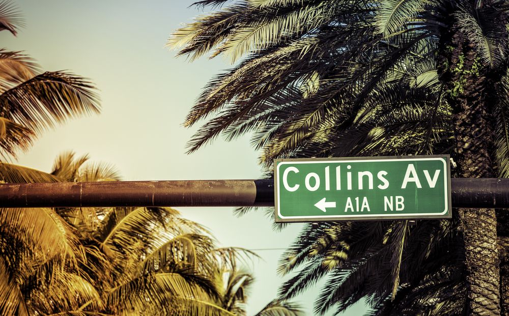 Signboard of Collins Avenue with palm trees in the background