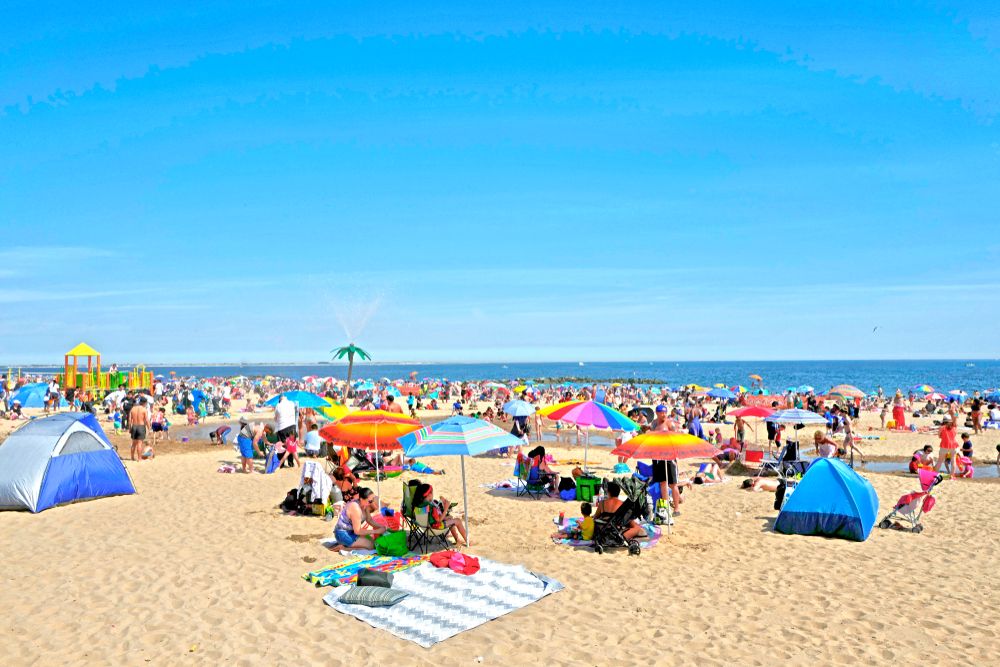 People sitting on the sands of Coney Island Beach