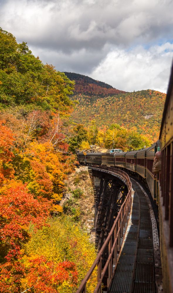 Train passiing through a bridge at Conway Scenic Railroad during fall