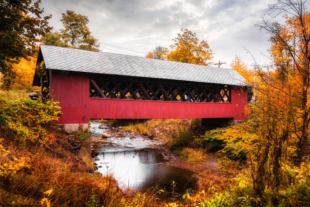 Side view of the Creamery Covered Bridge with a stream flowing beneath it
