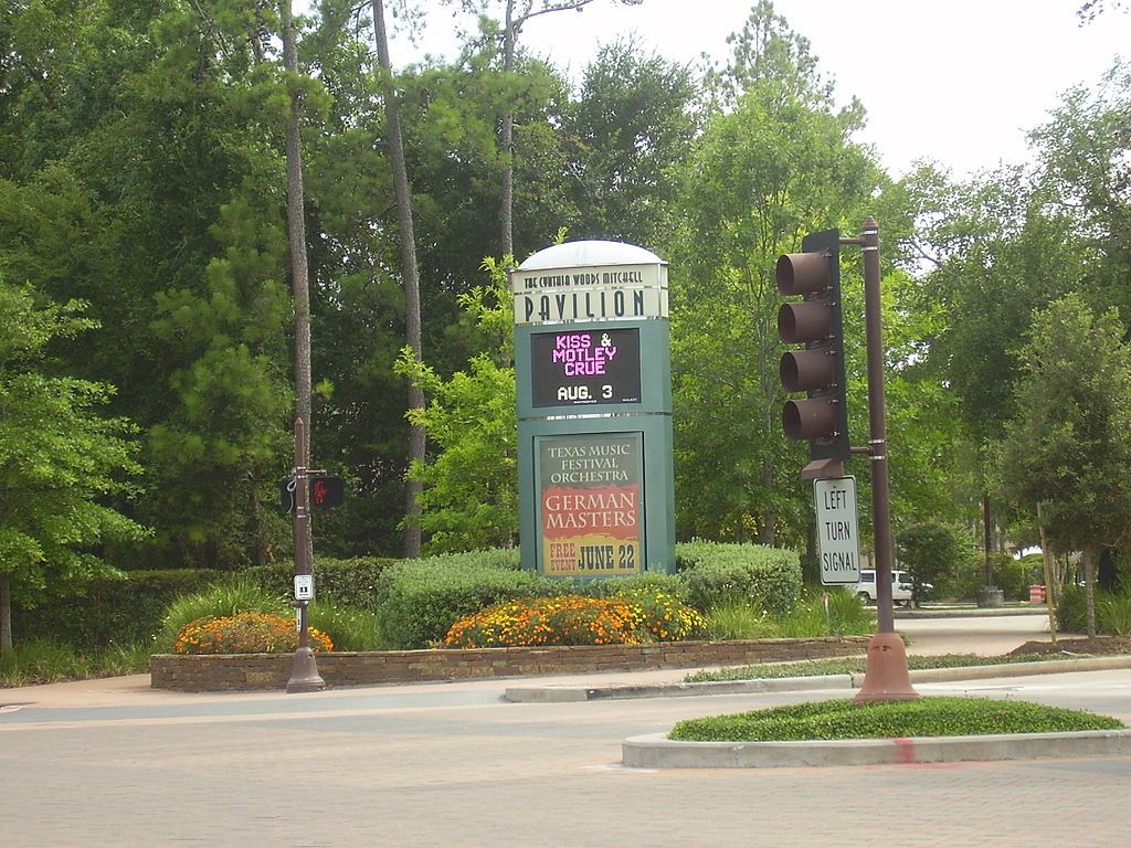 A welcoming signboard of Cynthia Woods Mitchell pavilion near a traffic light.