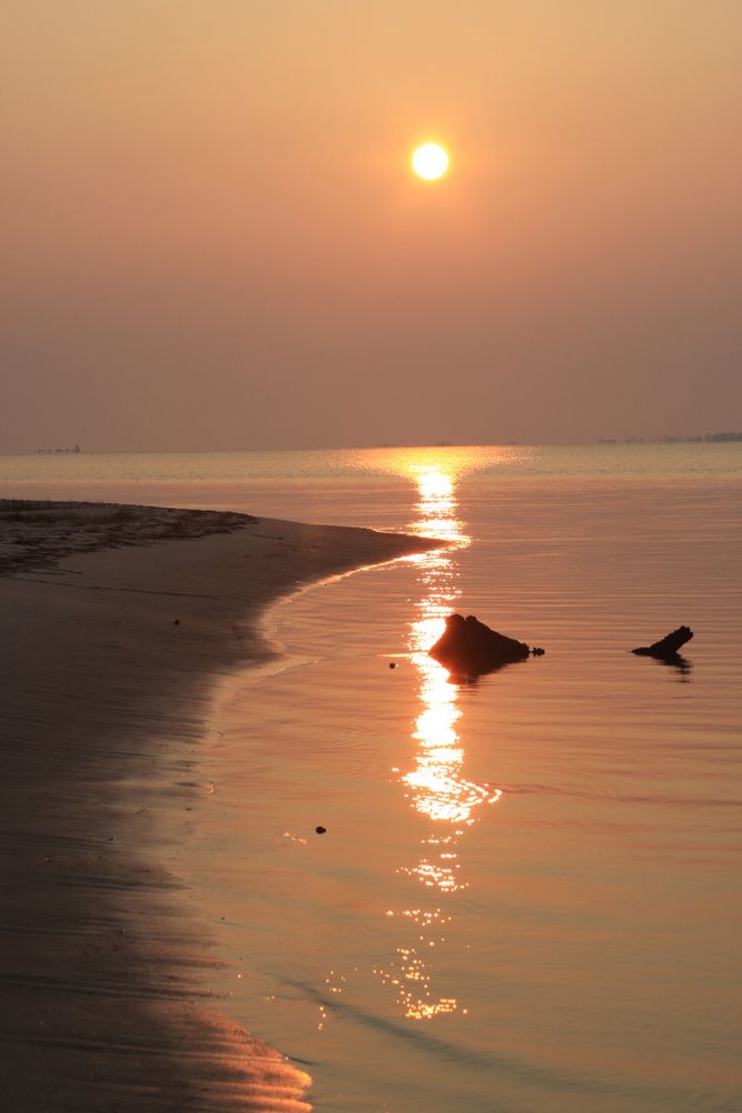Beautiful golden hour sunset reflecting on the still waters of the beach.