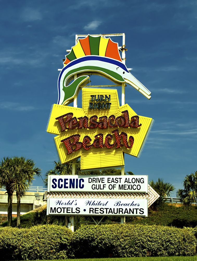 The bright yellow, green, red, and white colored pensacola beach sign.