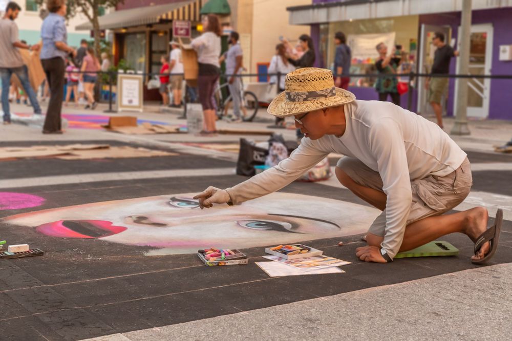 A  man paints a women's face at Lake Worth Street Painting Festival