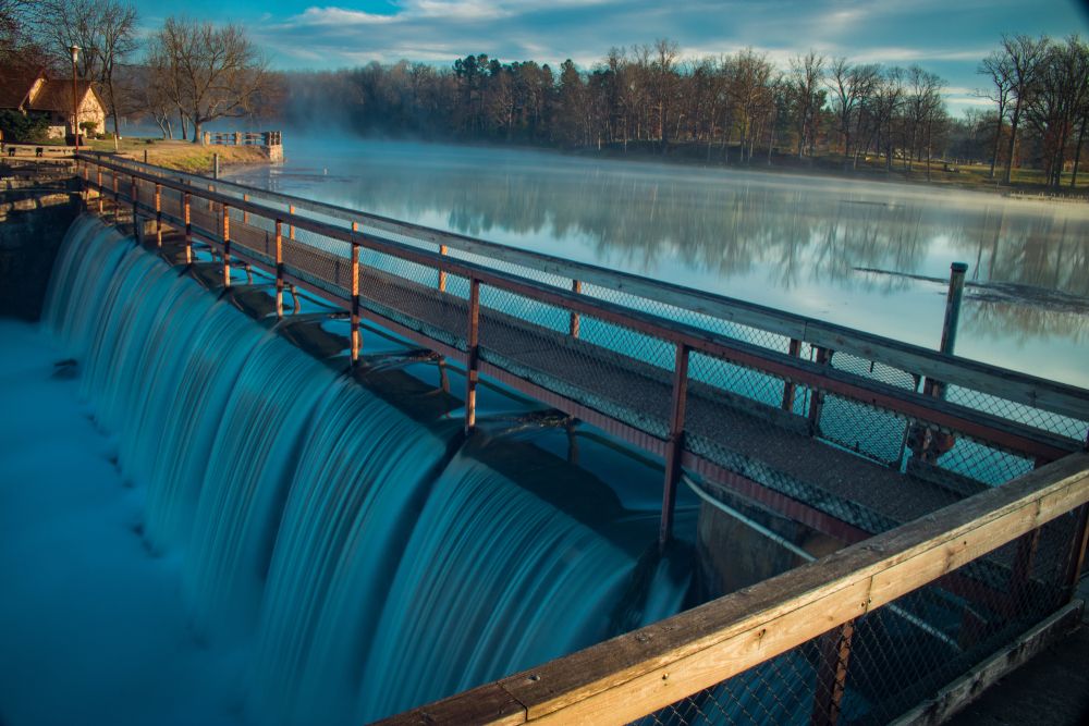 Picturesque view of the water flowing at Mammoth Spring State Park with a narrow bridge above it