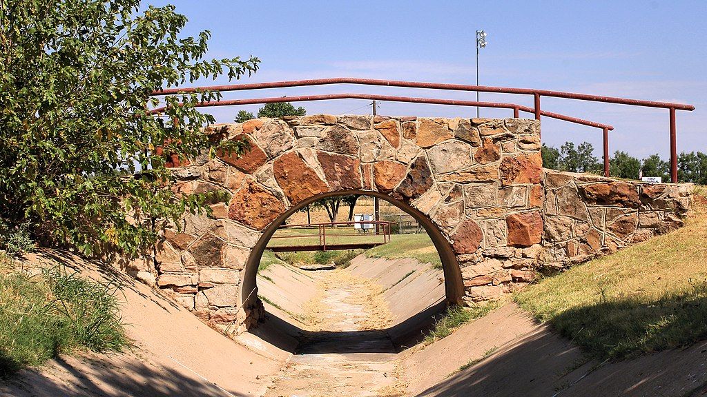 Stone bridge of Newman Park, with red-coloured railings.