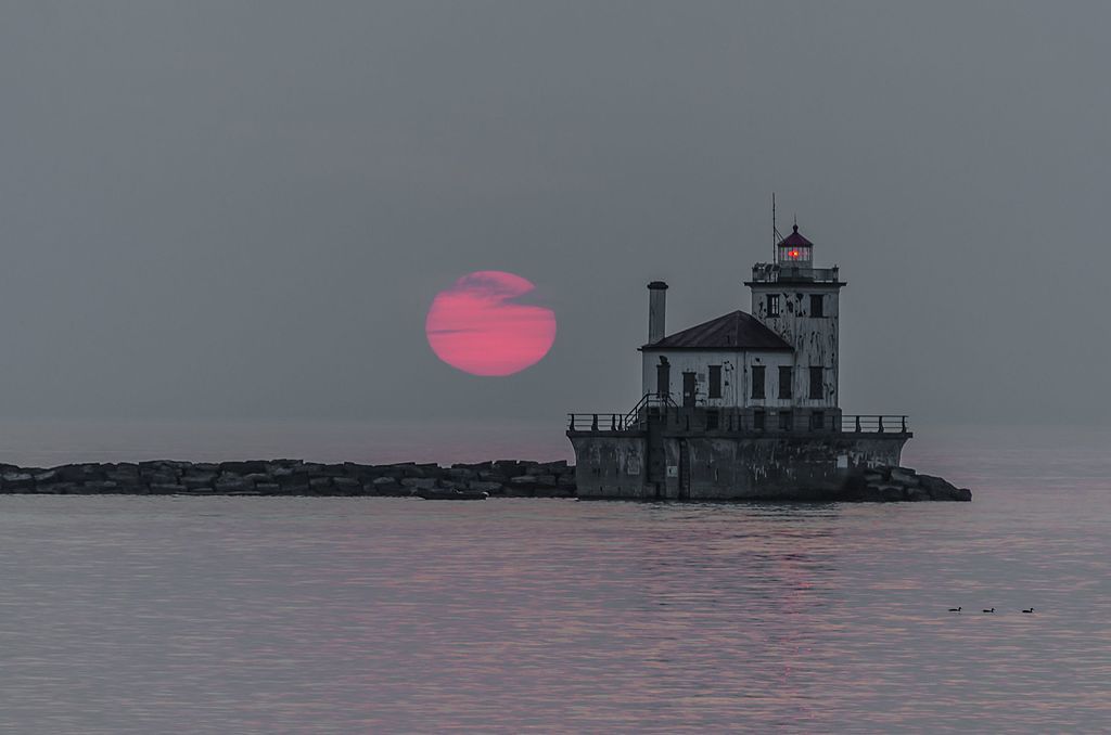 The West Pierhead lighthouse in the middle of a body of water - during a pink sunset