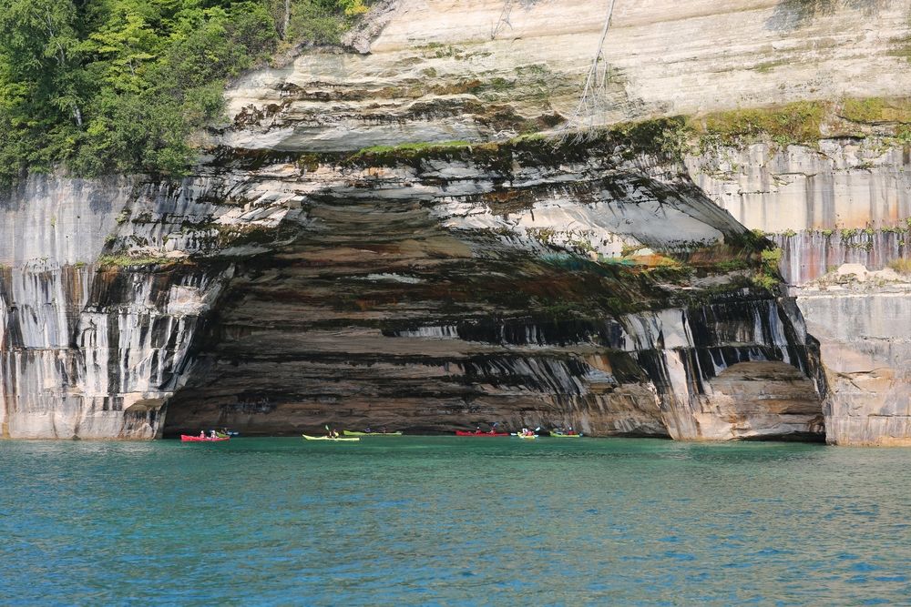 Paddlers paddling under a cave at Pictured Rocks