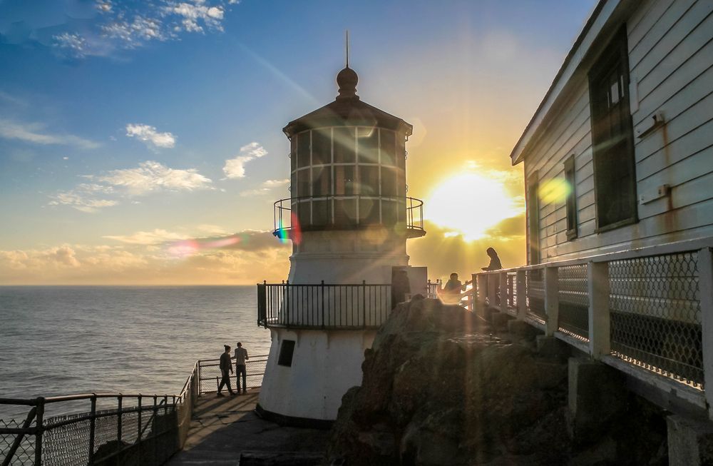 The setting sun peeking behind Point Reyes Lighthouse.