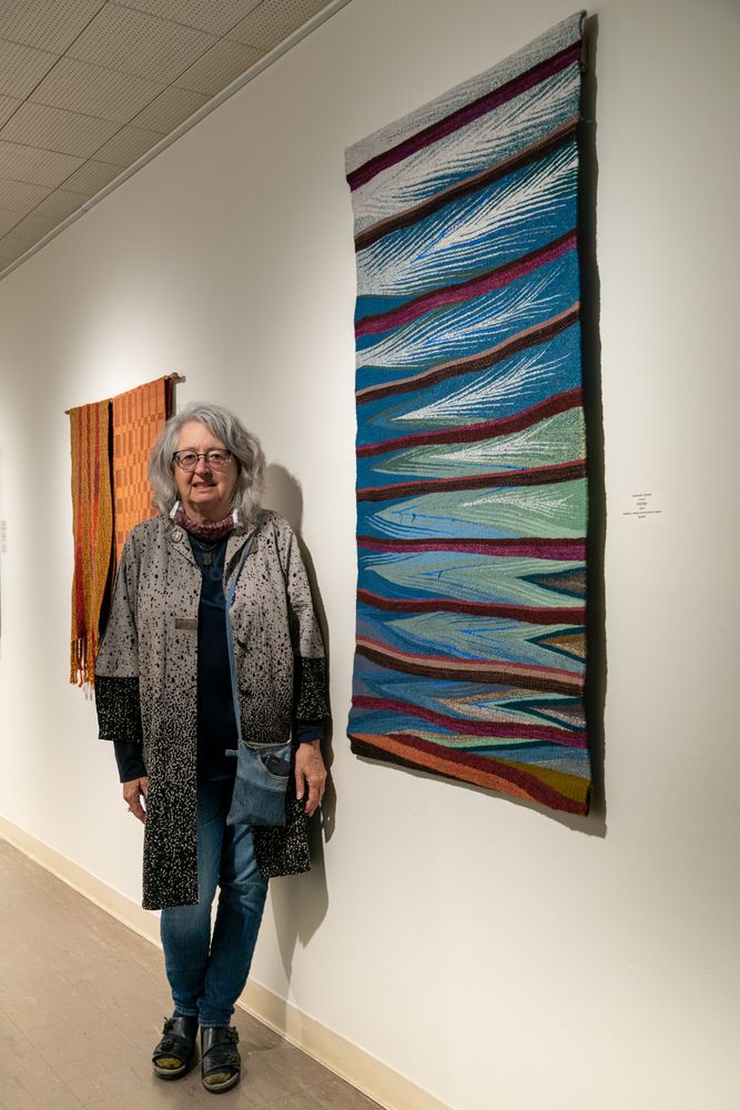 A woman posing in front of the tapestries at the Sanchez Art Center