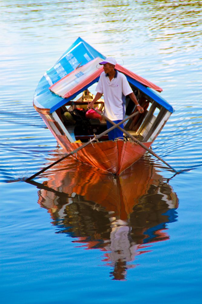 Closeup view of a boatman rowing his boat at Sarawak River