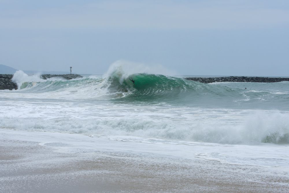 Big wave at The Wedge with rocks in the background