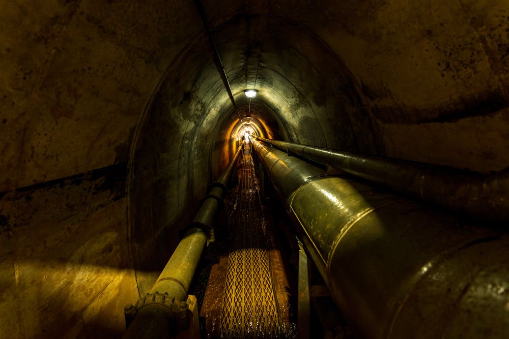 Dark tunnel with dim lights and oil pipes at WWII Oil Storage Tunnels