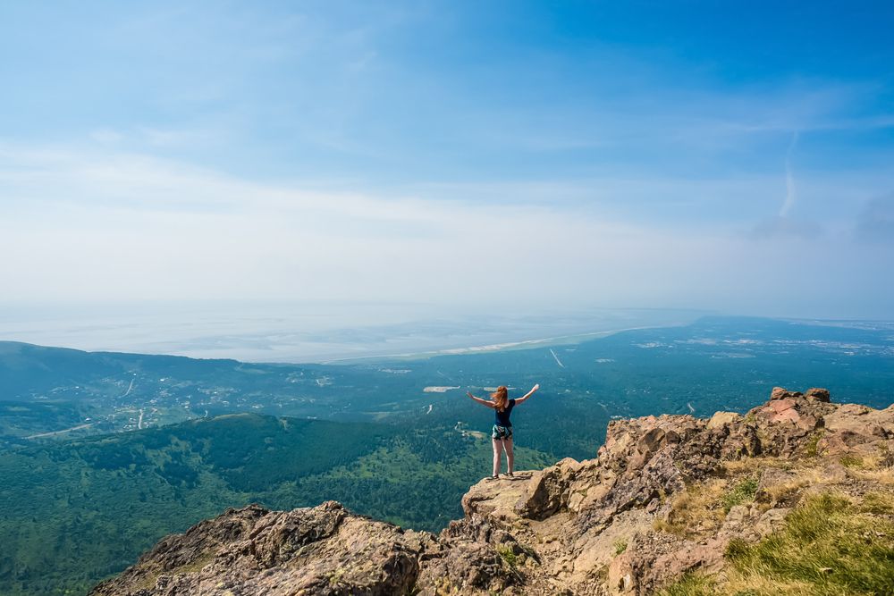A hiker standing on the edge of Flattop Mountain's summit