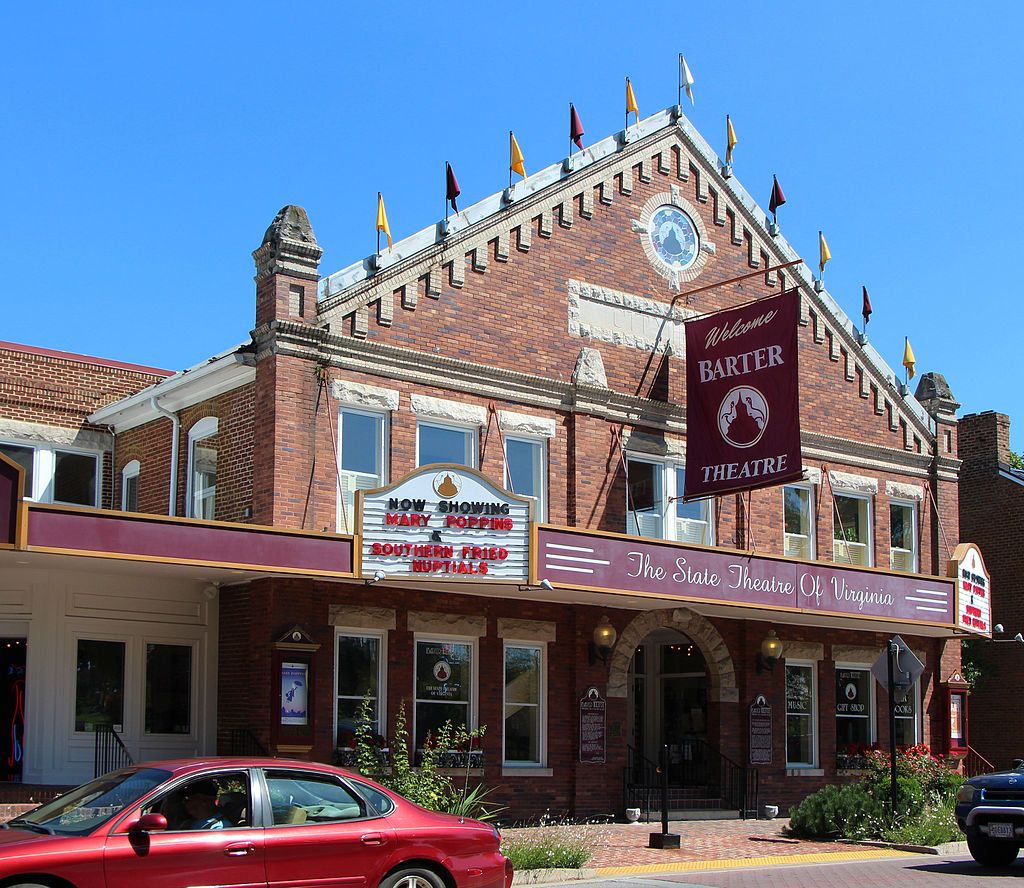 Exterior of the brick building of barter theatre with a red car parked in front.