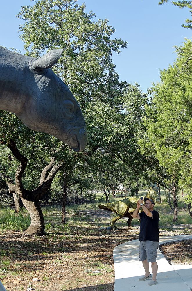A Man Taking Picture at a Dinosaur in Bandera Natural History Museum