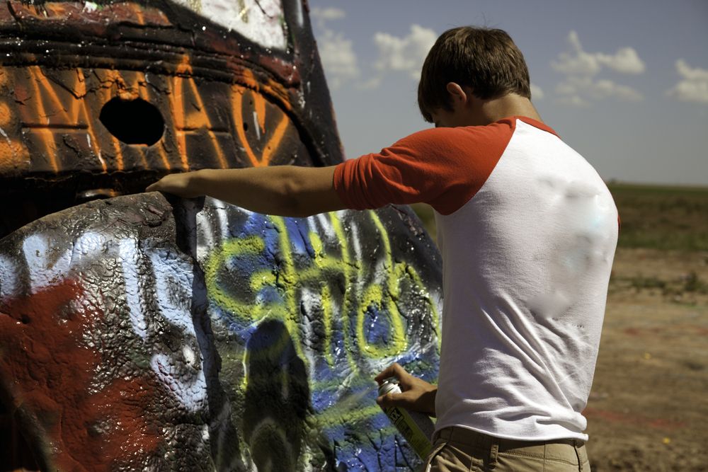 A person spray-painting a car at Cadillac Ranch