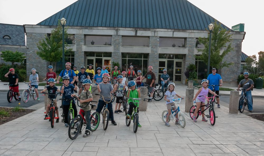 Kids posing on their bikes in front of the kentucky artisan center.