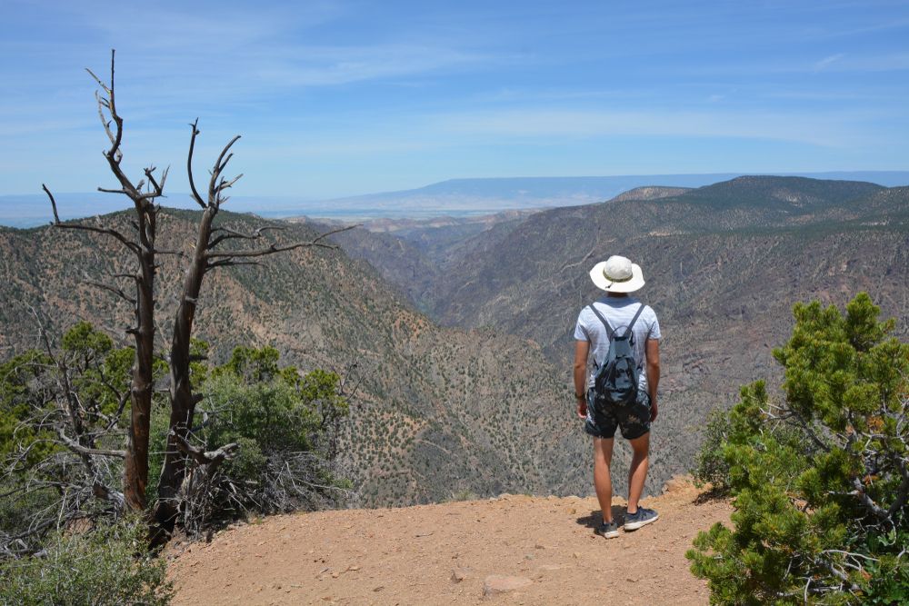 A hiker standing at the peak on one of black canyon's trail