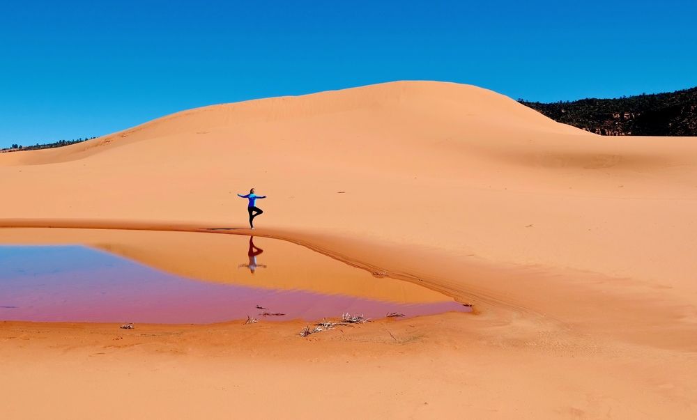 A woman doing yoga in Coral Pink Sand Dunes State Park