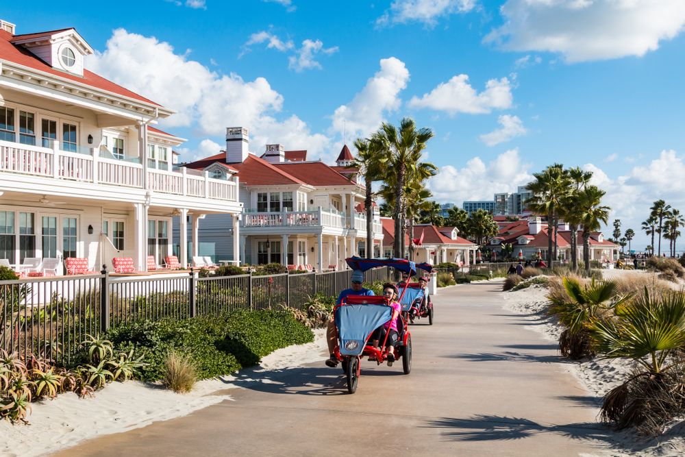 People riding surrey bikes in front of Hotel Del Coronado