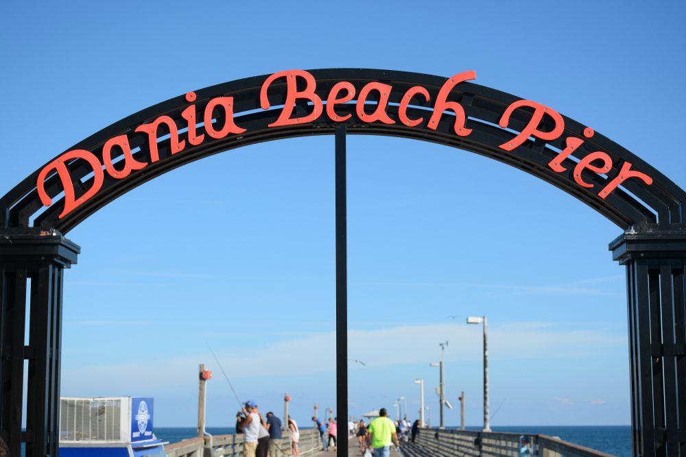 Black arch welcoming sign of Dania Beach Pier written in red.