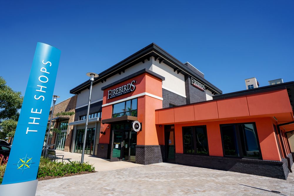 "The shopps" name sign in front of an orange and white building.