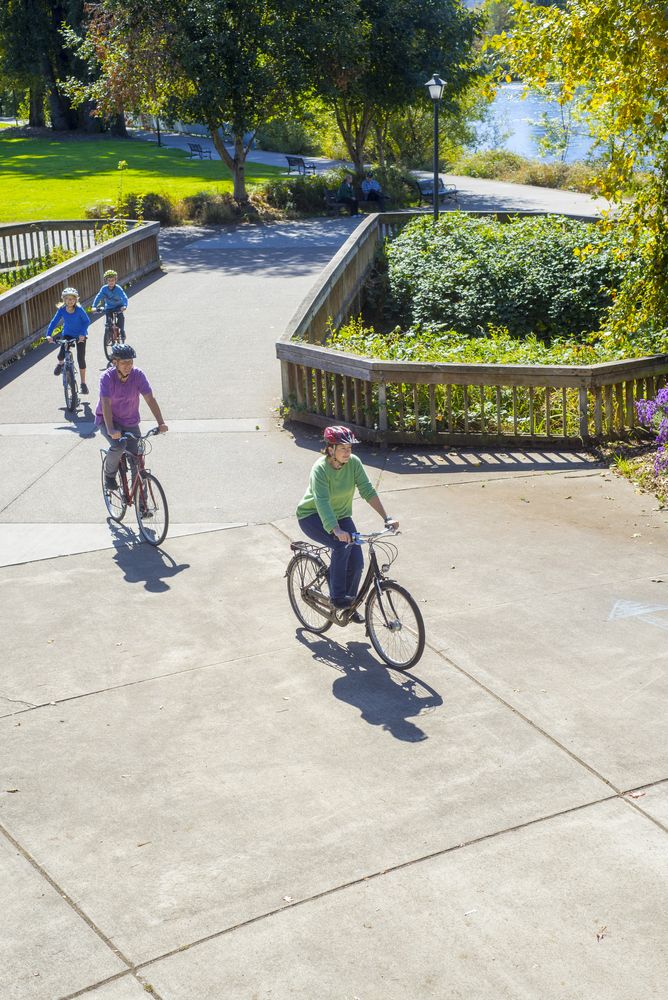 A family of four riding bikes along Alton Baker Park
