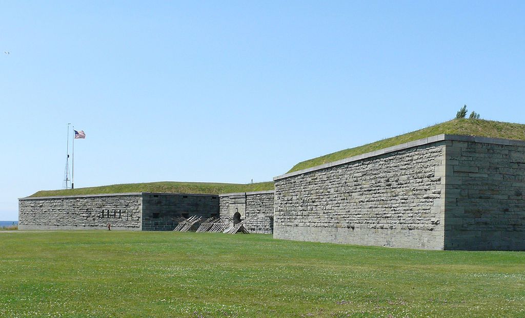 View of lon, blockk walls, green grass, and the U.S.A flag.