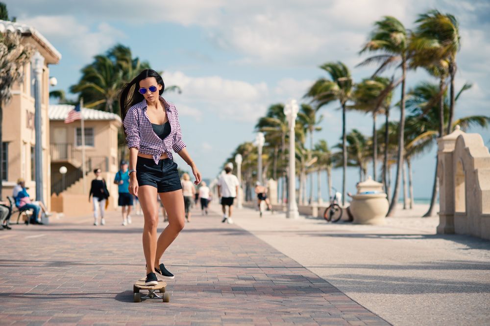 A woman riding a skateboard along Hollywood Beach Broadwalk