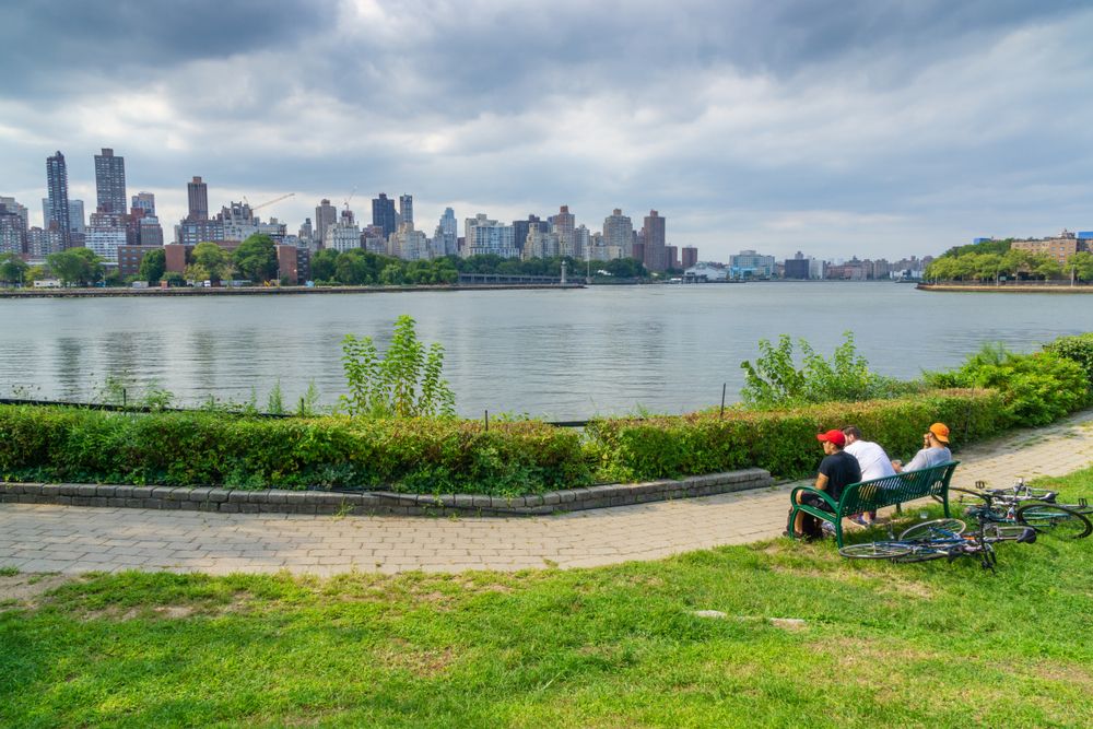 Three men sitting on a bench near the river.