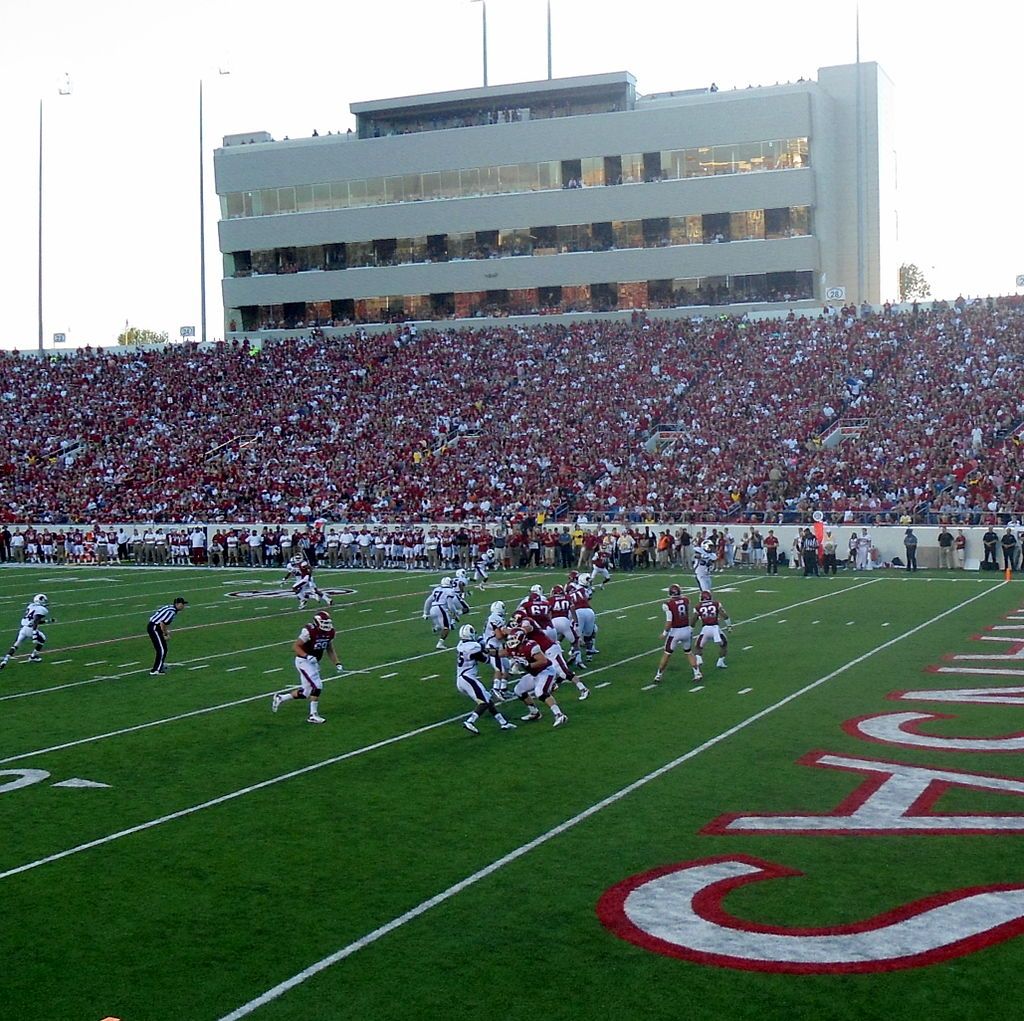 Teams playing football will thousands of audience seated at the benches.