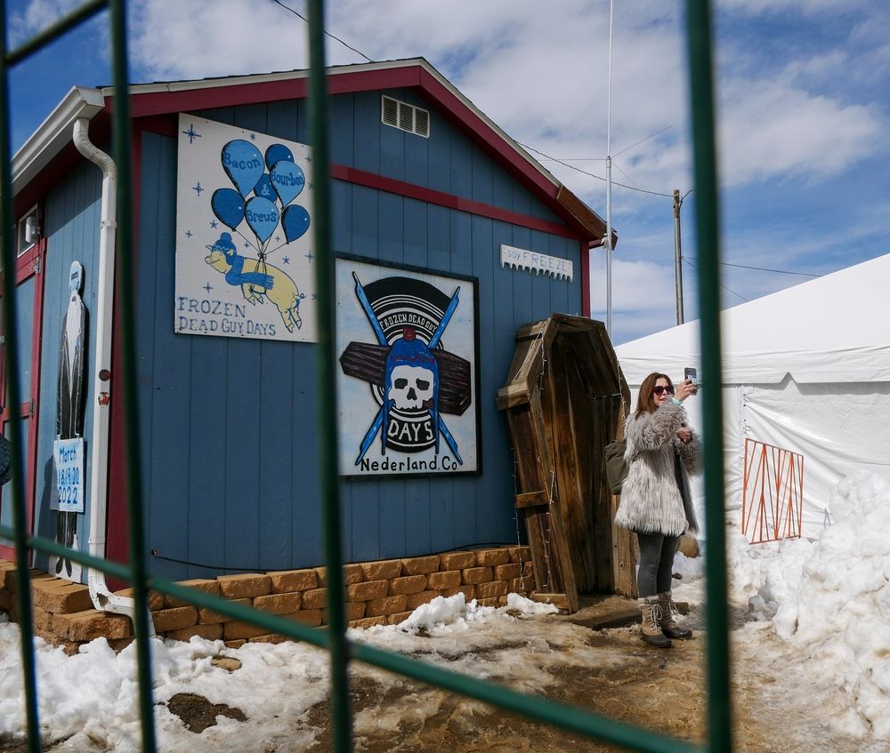 A person taking a picture in front of Frozen Dead Guy Days coffin