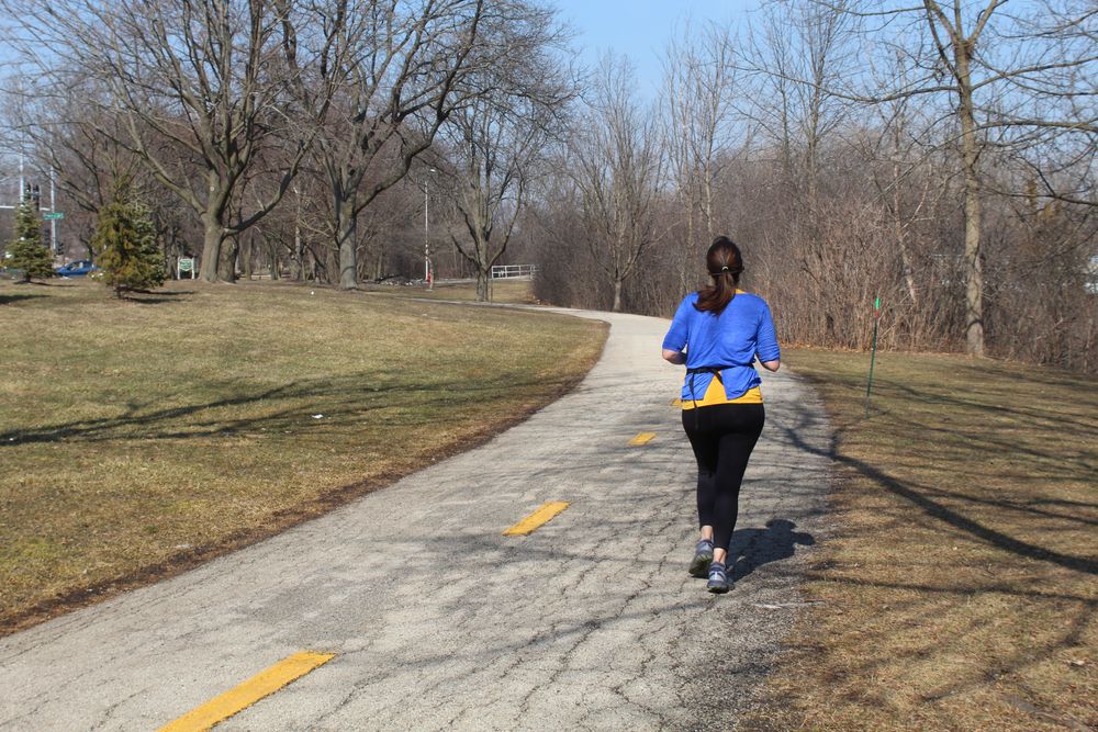 A woman jogging along Skokie Northshore Sculpture Park