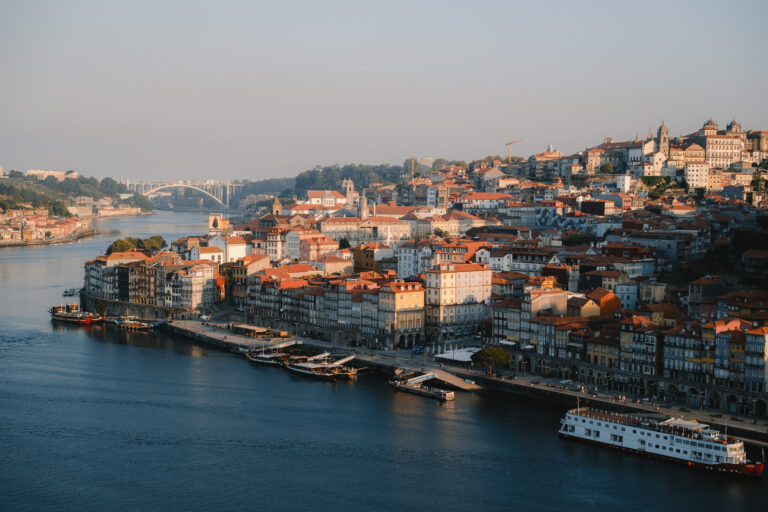 The golden hour casts a warm glow over the charming Ribeira district along the Douro River in Porto