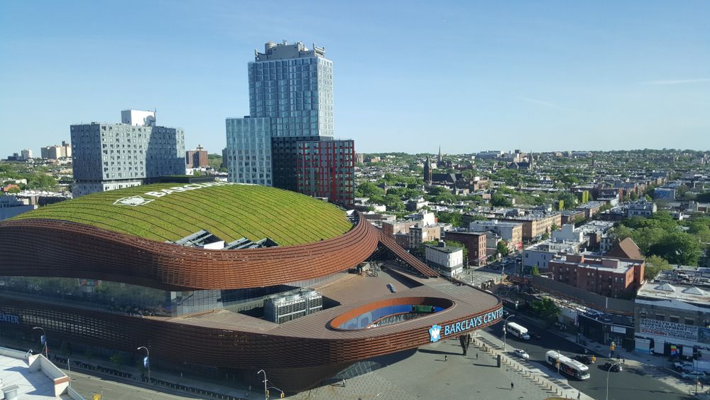 Aerial view of the barclays center building with city skyscrapers behind it.