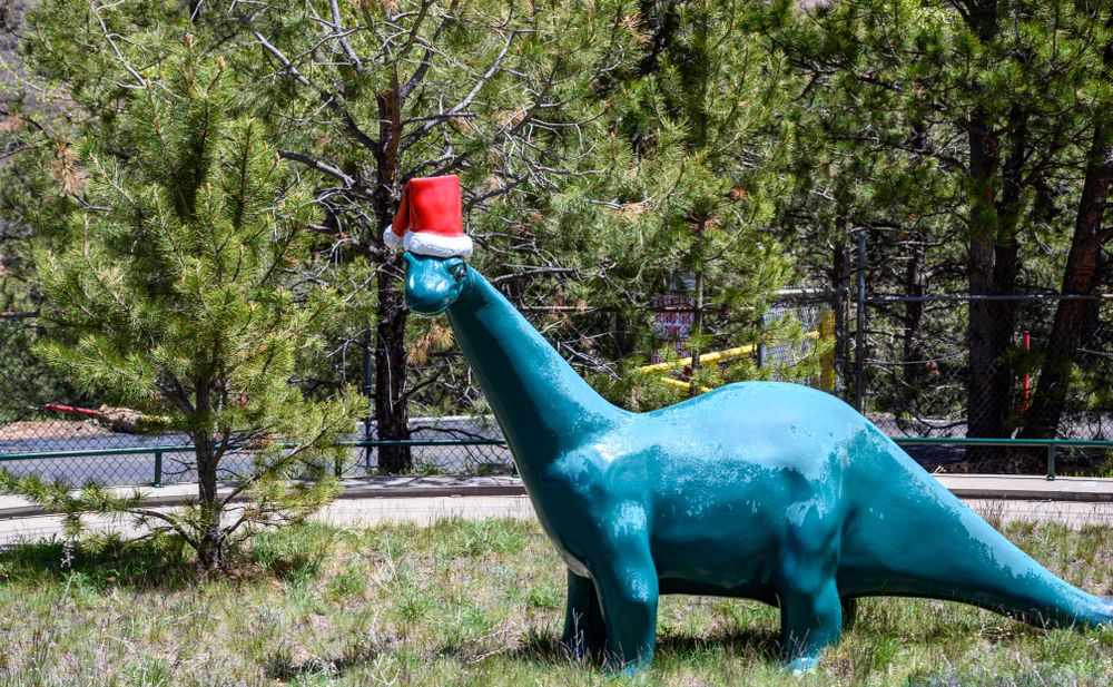 Dinosaur sculpture wearing a santa hat at North Pole Colorado Santa’s Workshop