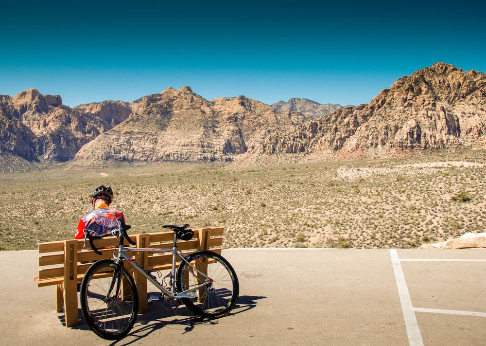 A man resting on a bench with his bike
