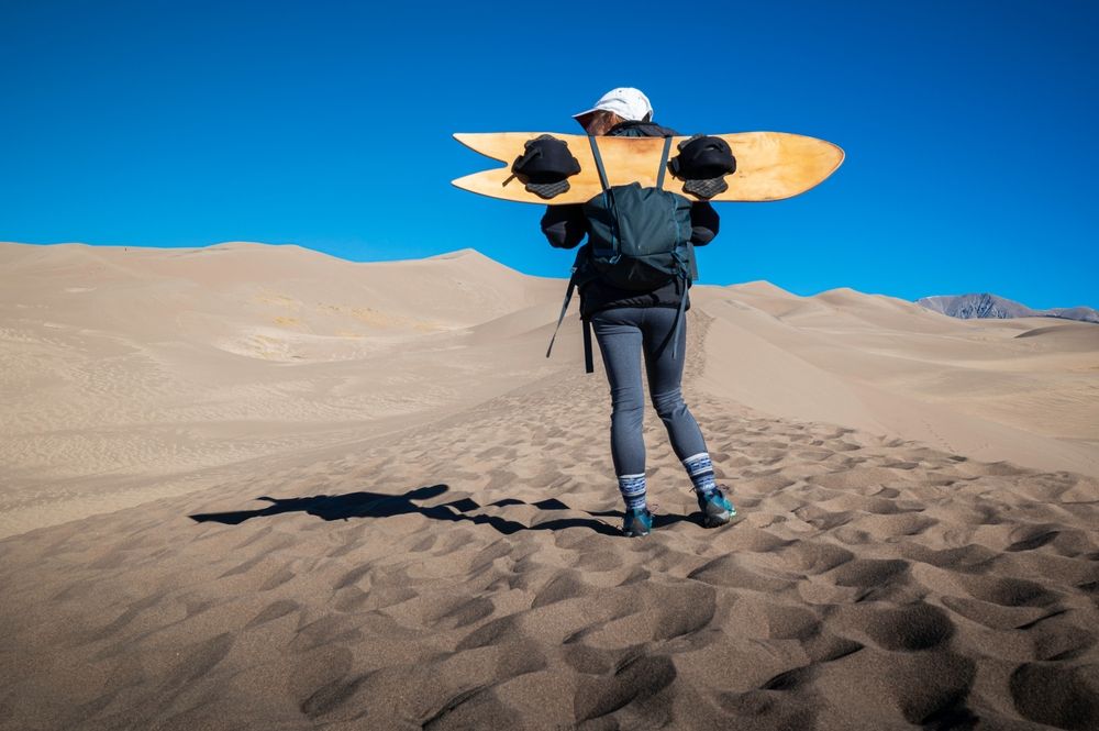 Hiker with a sand-board at Great Sand Dunes National Park & Preserve
