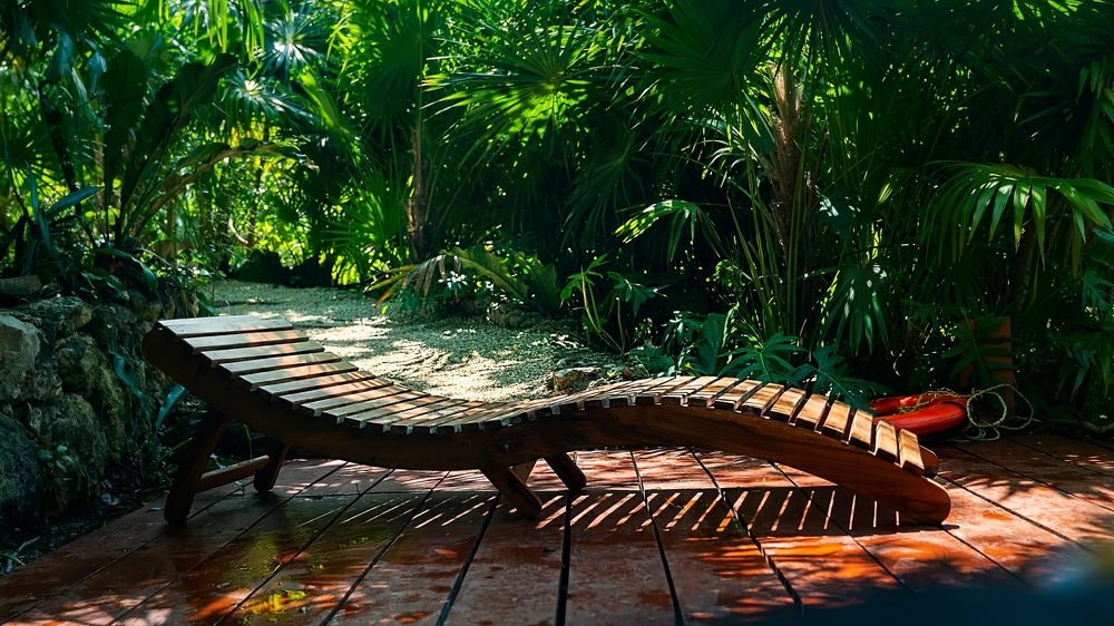 A wooden lounge chair surrounded with plants at Kantun Chi Eco Park
