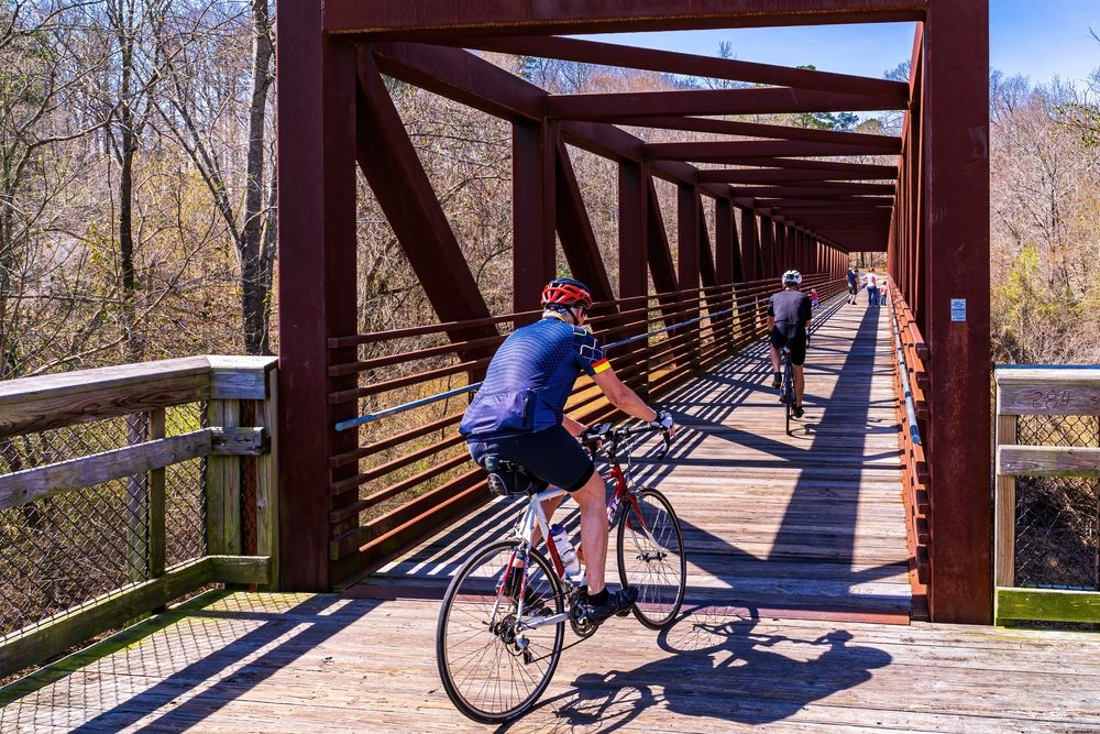Cyclists along Neuse River Greenway Trail's iron bridge