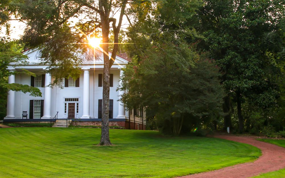 The sun peeking behind the bulloch hall building.