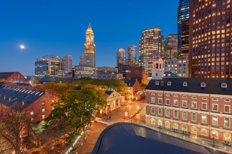 A dusk view over Faneuil Hall and Quincy Market, showcasing the illuminated skyline of Boston, Massachusetts, USA.