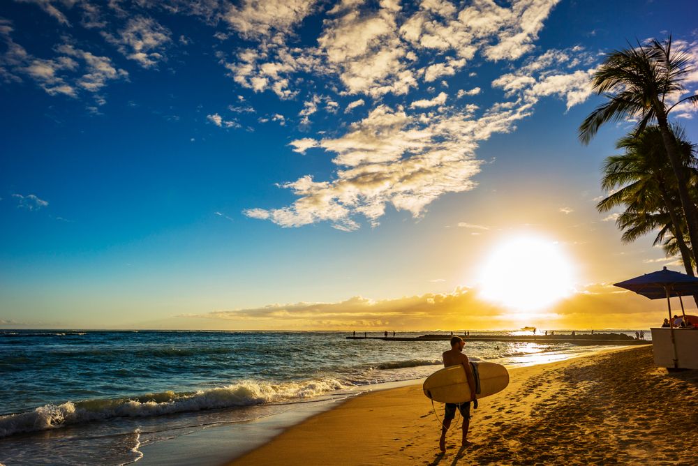A surfer walking along Waikiki Beach