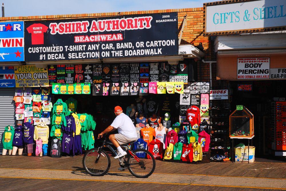 A person riding a bike passing by a shirt shop