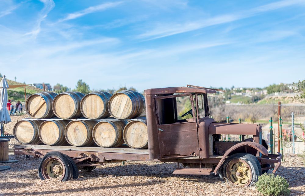 Old Rusty Vintage truck on display at vineyard with wooden wine barrels on top in Temecula