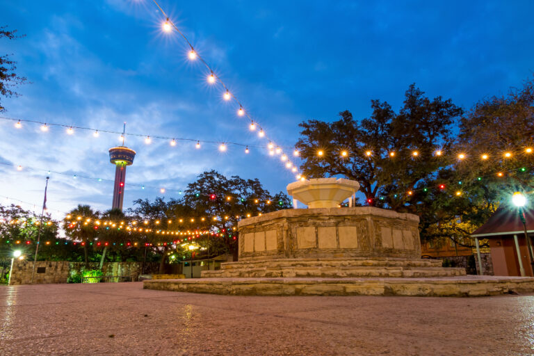Strolling along the River Walk in San Antonio, twinkling lights overhead cast a magical glow on the serene evening.
