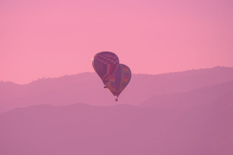 A serene hot air balloon floats above the rolling hills of Temecula Valley, CA, basking in the warm glow of the sunset.